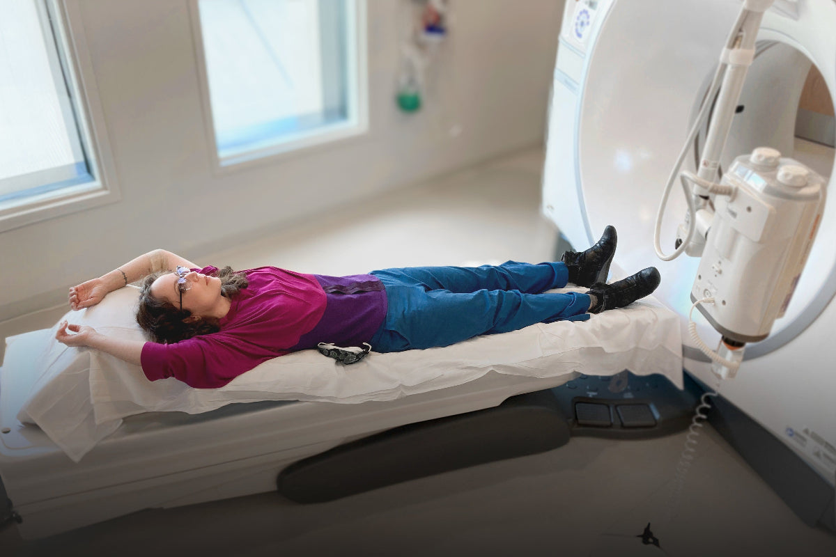 Woman in a CT scan bed, wearing her medically accessible and scan ready adaptive wear clothing, so she doesn't have to take off her clothes and wear a horrible robe