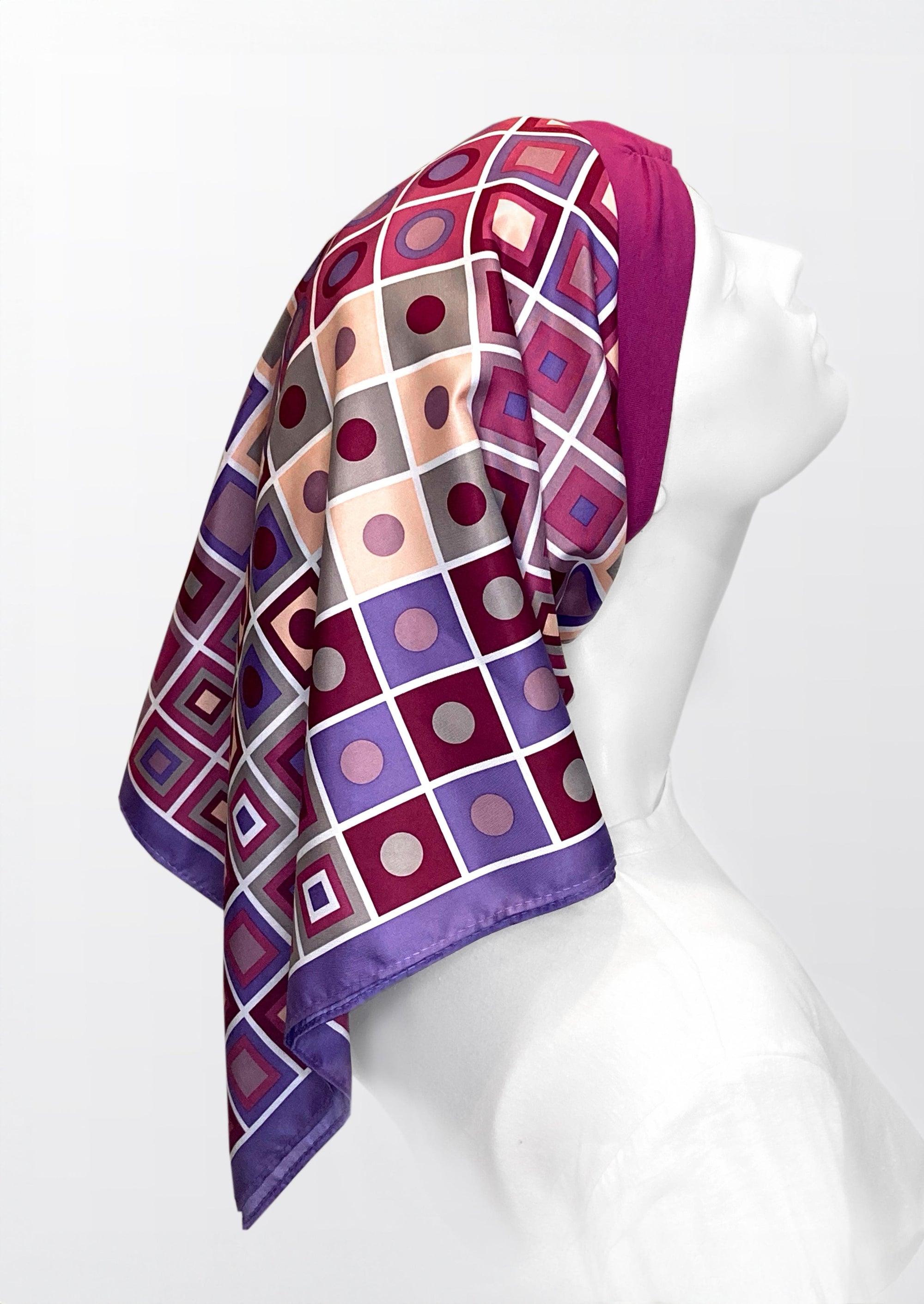 beautiful woman wearing a fashionable headscarf, of pink and lavender with geometric shapes , in the retro kerchief style, designed specifically for those experiencing hair loss