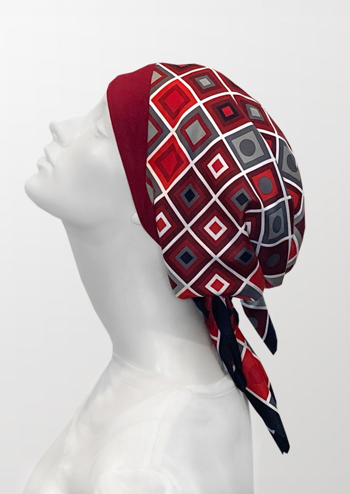 Fashionable headscarf, of ruby red and black with geometric shapes , in the retro kerchief style, designed specifically for those experiencing hair loss.