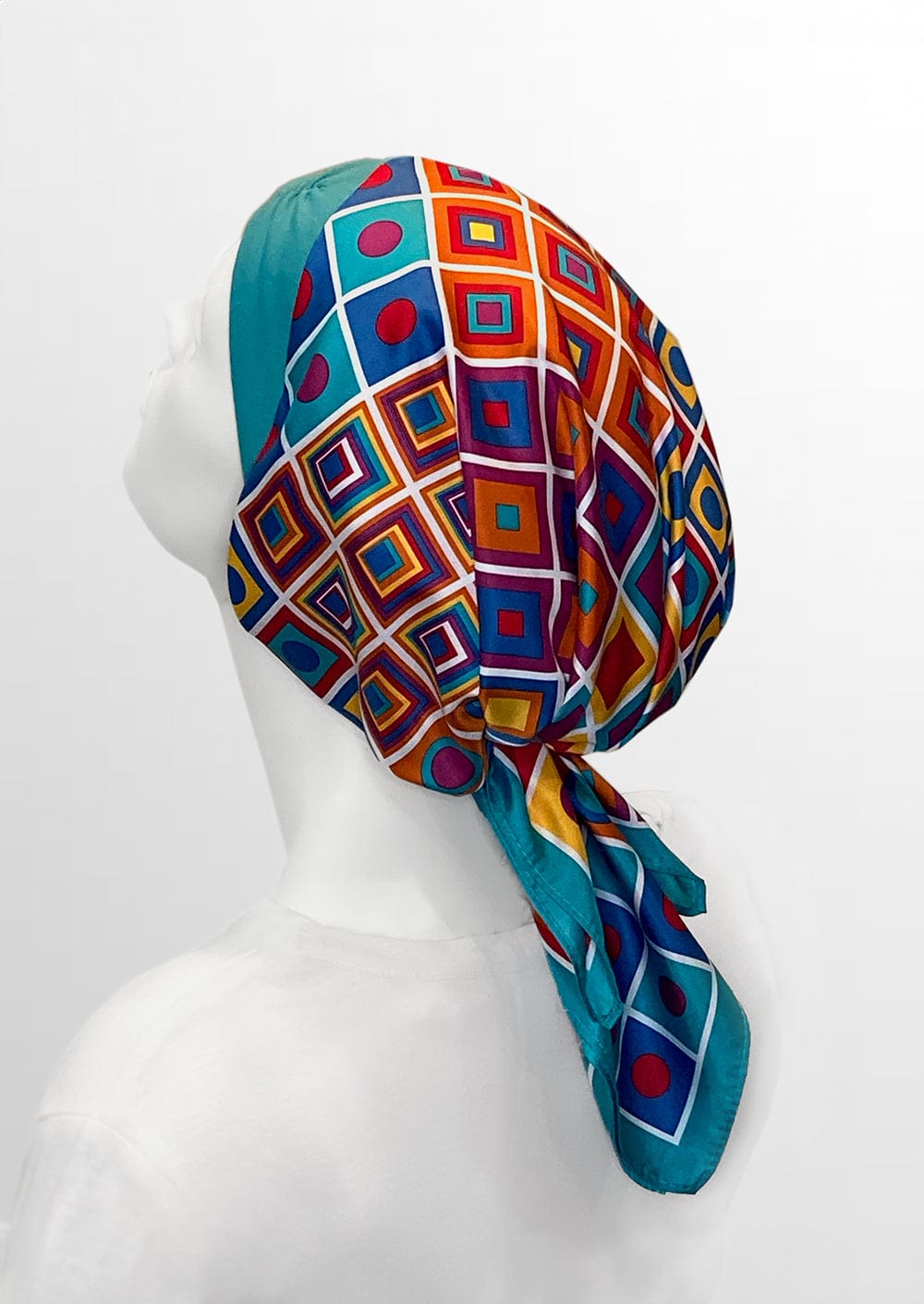 beautiful woman wearing a fashionable headscarf, of Teal  headband and matching and multi color geometric shapes , in the retro kerchief style, designed specifically for those experiencing hair loss