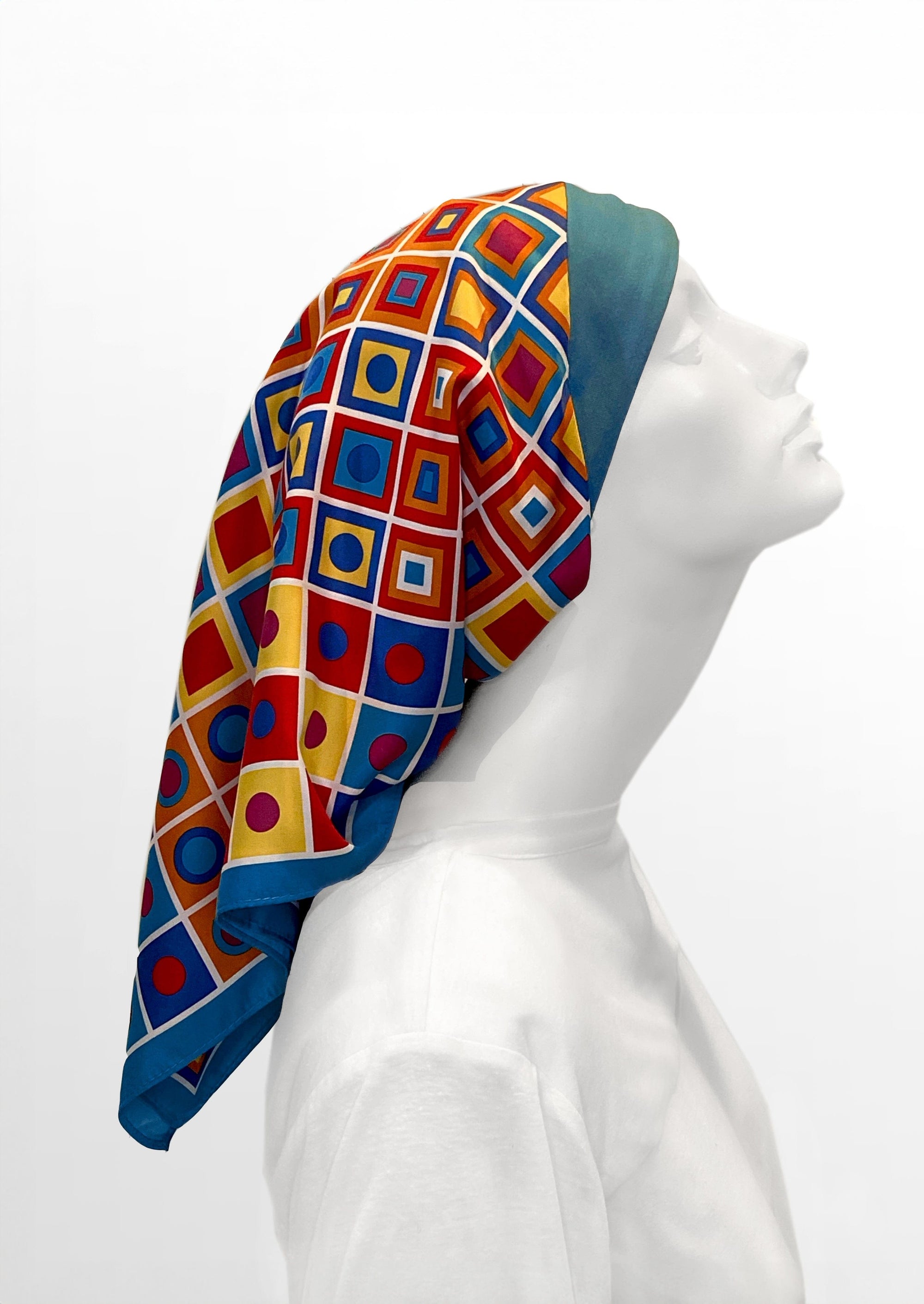 Fashionable headscarf, of teal  headband and matching and multi color geometric shapes , in the retro kerchief style, designed specifically for those experiencing hair loss. side